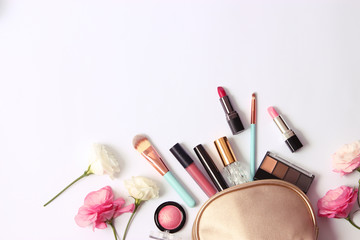 Cosmetics and flowers on a light background top view.