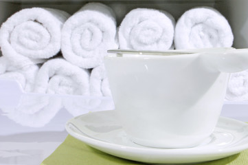 Fototapeta na wymiar A cup of coffee on the background of individual towels, folded roller. Kotsept convenience and service for customers cosmetology cabinet.