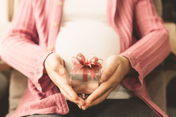 Pregnant woman feeling happy at home while taking care of her child. The young expecting mother...