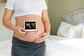 Pregnant woman feeling happy at home while taking care of her child. The young expecting mother...