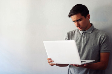 Man dressed in gray using a white laptop.