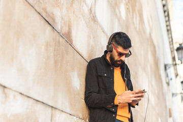 Obraz premium Young Hipster Man Using Cell Phone and Listening Music .