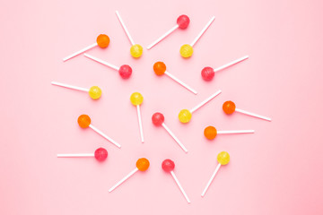 Pink, orange and yellow sweet candy lolipop on a pastel pink background