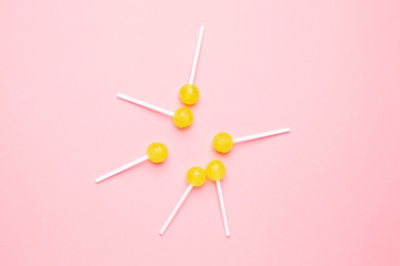 Sweet yellow candy lolipop on pastel pink background. Minimalist composition.