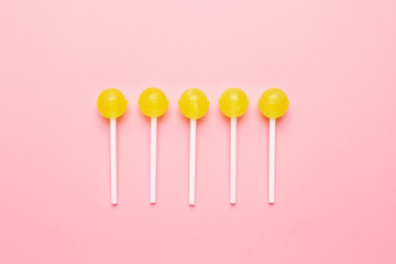 Sweet yellow candy lolipop on pastel pink background. Minimalist composition.