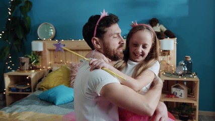 Family happy life moments. Close-up lovely girl and her father pretty fairies hugging and kissing together in bedroom. Home fancy costume party.