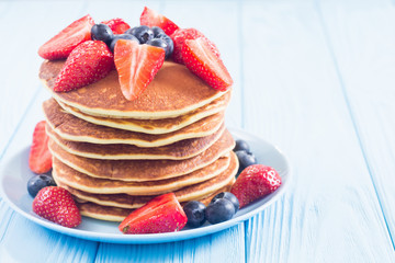 Tasty pancakes with blueberry and strawberry