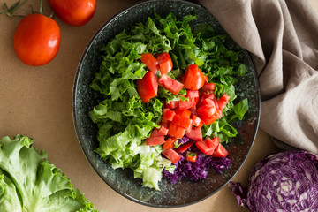 salad with tomatoes,lettuce,red cabbage and olive oil in the plate on the black background.
