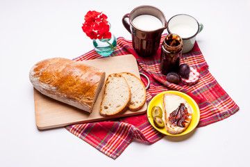 Bread with plum jam cup of milk on white.