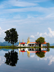 Pagoda with golden spires on a little island on the mirroring Lake Inle, Myanmar/Birma.