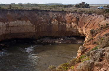 A white SUV car at the top of a huge cliff in the Bay of Islands on the Great Ocean Road in Australia