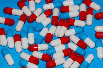 colorful red and blue white capsules are lying in the blue studio