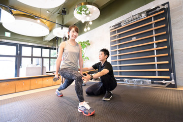 トレーニングジムで下半身を鍛える女性（ダンベルで重しをつける）