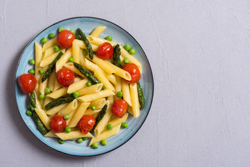 Penne pasta salad with asparagus , tomatoes and peas