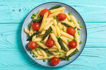 Penne pasta salad with asparagus , tomatoes and peas