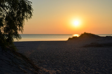 Fototapeta na wymiar Sunset by an empty sandy beach