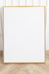 empty golden frame with white wall on wooden floor.