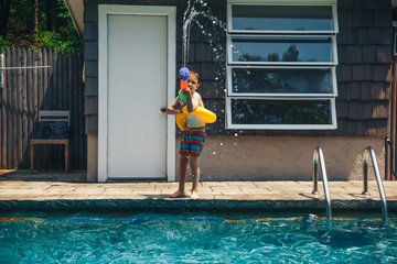 boy having fun in the pool with water gun. the water battle