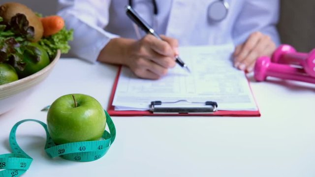 Nutritionist with healthy fruit, vegetable and measuring tape working, Right nutrition and diet concept