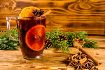 Cup of mulled wine with cinnamon and fir tree branches on wooden table