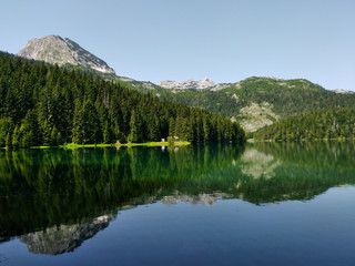 lake with reflection of mountains in national park in montenegro
