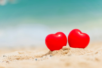 Fototapeta premium Two Hearts couple lover symbol on honeymoon day trip in tropical paradise island with banner copy space. Romantic red hearts objects on wedding anniversary for couple lover. Honeymoon tourism concept.