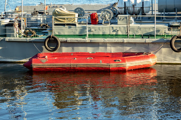 Fototapeta na wymiar red rescue inflatable boat at the side of a warship