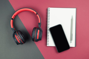 Top view of notebook with pen smartphone and headphone