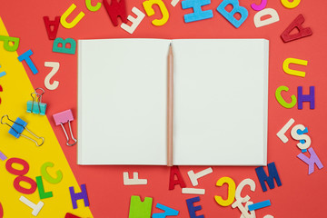 Top view of blank open notebook with pencil and alphabets