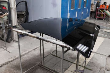 Painting and drying in a professional box of car body parts after applying putty and paint hood in...