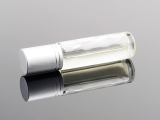 Silver color cosmetic spray bottle horizontally on gray background with reflection