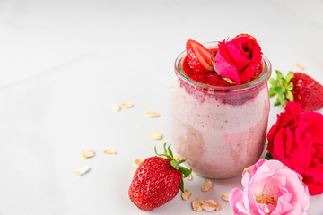 romantic healthy breakfast. overnight strawberry oats with fresh berries and mint with rose flowers in a glass