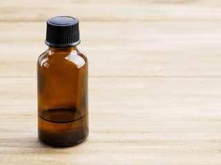 Empty yellow glass bottle with black cap for aromatherapy products on wooden background