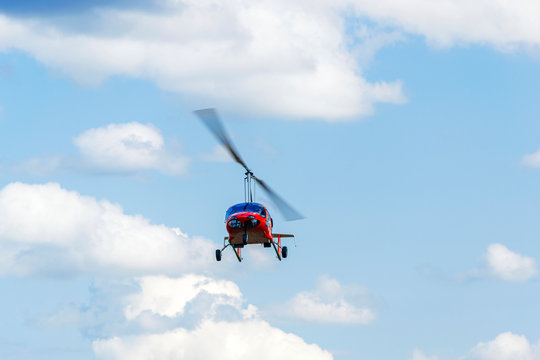 Red gyroplane in flight
