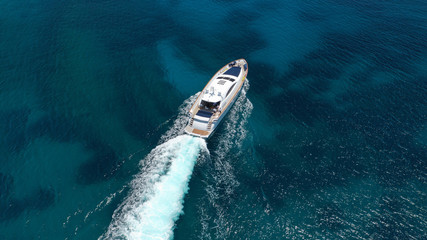 Aerial drone tracking photo of luxury yacht with wooden deck cruising in deep blue waters of Mykonos island, Cyclades, Greece