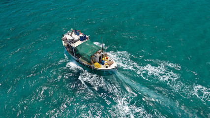Aerial top view photo of big traditional fishing boat cruising in emerald sea near port of Paros island, Cyclades, Greece