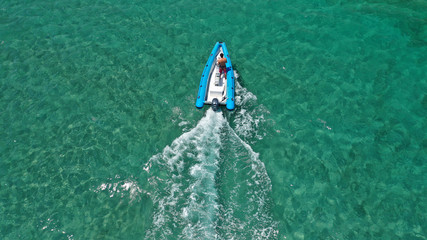 Aerial bird's eye view of inflatable rib boat cruising in high speed in turquoise clear water sea