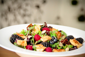 Healthy salad bowl with grilled chicken, caramelized onion and berries.