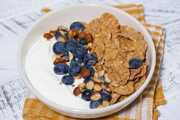bowl of healthy wholegrain flakes, yogurt and blueberries