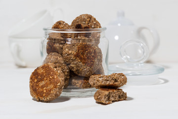 glass jar with oatmeal cookies on white background