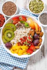 oatmeal porridge with fresh fruit and superfoods for healthy breakfast, vertical closeup