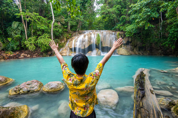 A freedom man is enjoying with beautiful waterfall in tropical forest