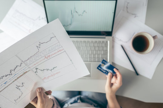  Top view. Woman using laptop and credit card for buying on-line on stock exchange. pay and commerce.shopping.graphics and charts - Powered by Adobe