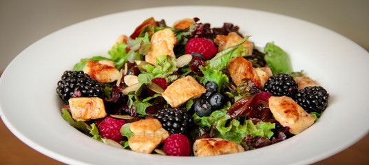 Healthy salad bowl with grilled chicken, caramelized onion and berries.
