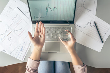 Top view. Tired business woman  holding a headache pill on the workplace with glass of water on the background of graphics and charts printed on the paper.