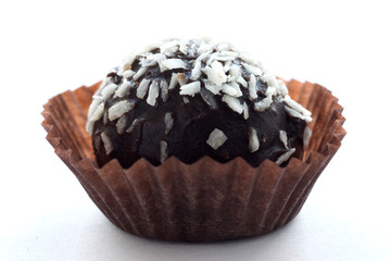 Beautiful chocolate cake sprinkled with coconut in a paper mold isolated on a white background