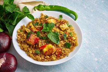 vegetarian paneer biryani at blue background. paneer biryani is traditional veg indian cuisine dish with paneer, basmati rice, masala, chili, mint. Copy space