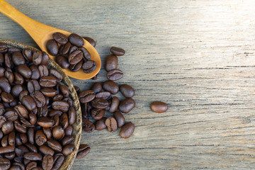 Coffee beans in a wooden spoon on a wooden background