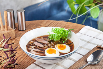 Fresh spicy soup with duck, egg, mushrooms and noodle. Traditional vietnamese noodle soup in bowl. Asian/vietnamese cuisine. Copy space for design. Served lunch in restaurant. Close up