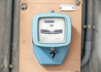Old electric meter on a wooden panel